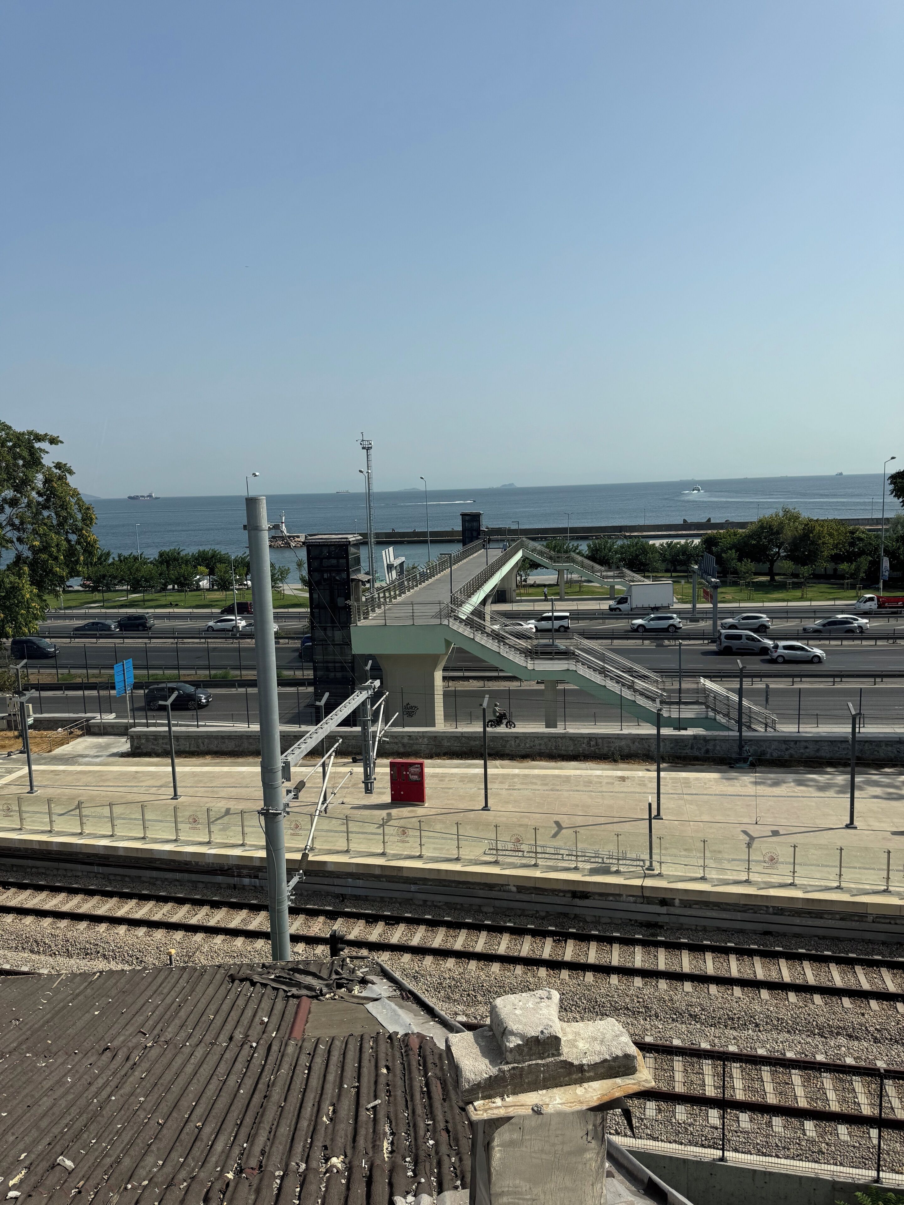 A coastal view with a bridge, parking area, and a train station platform.