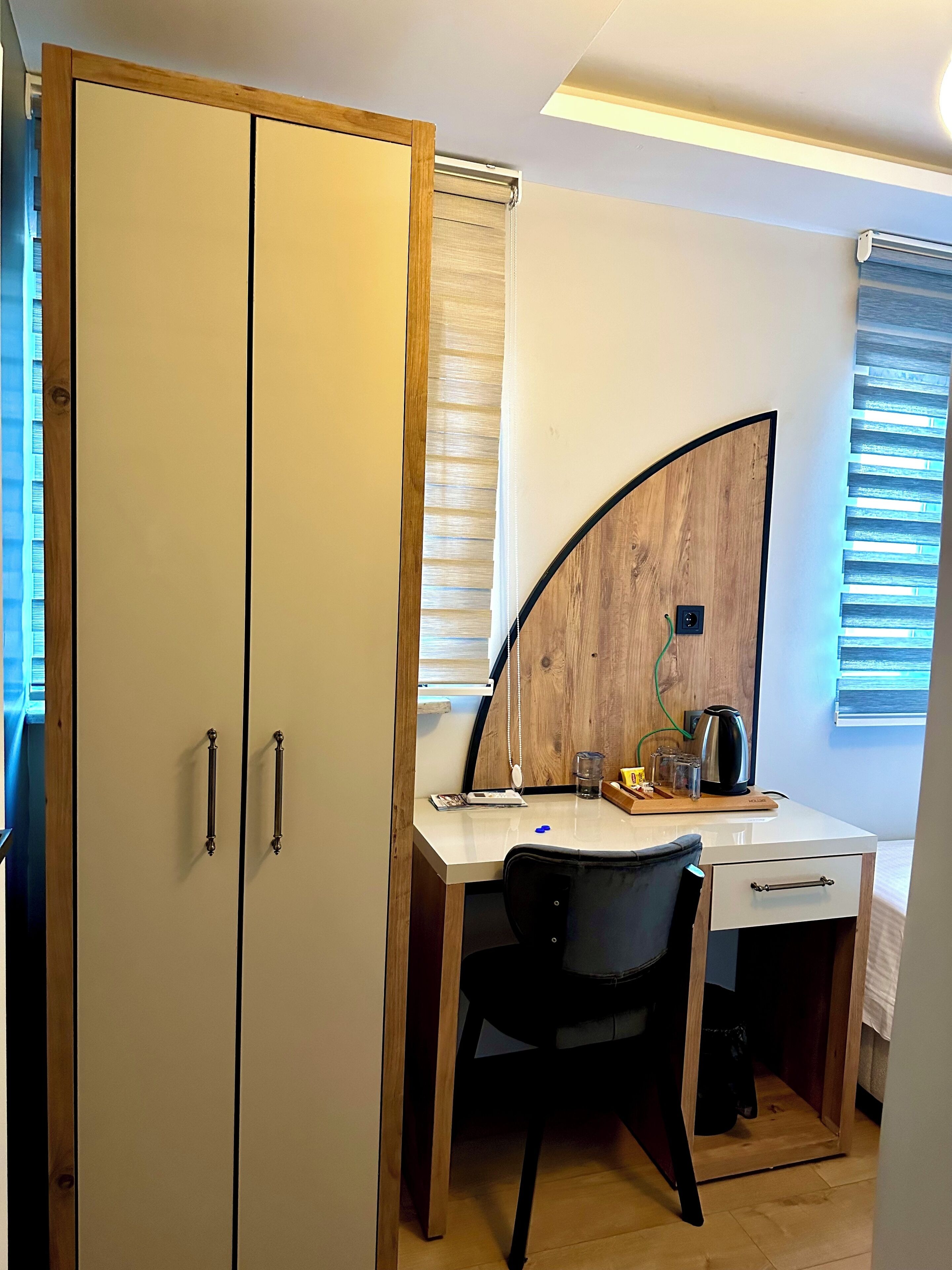 Un dormitorio compacto con cama, escritorio con silla, armario y un espejo curvo.