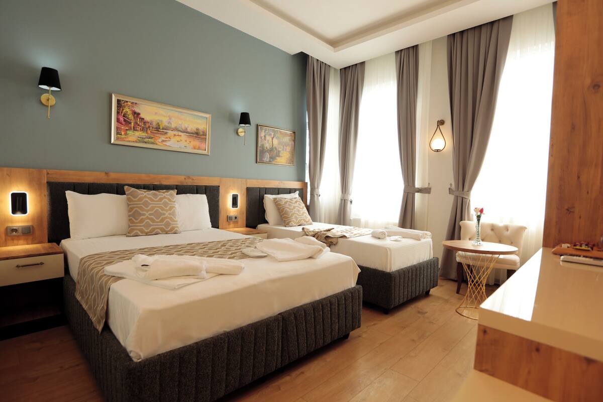 A hotel room with two beds, a small round table, and a nightstand.