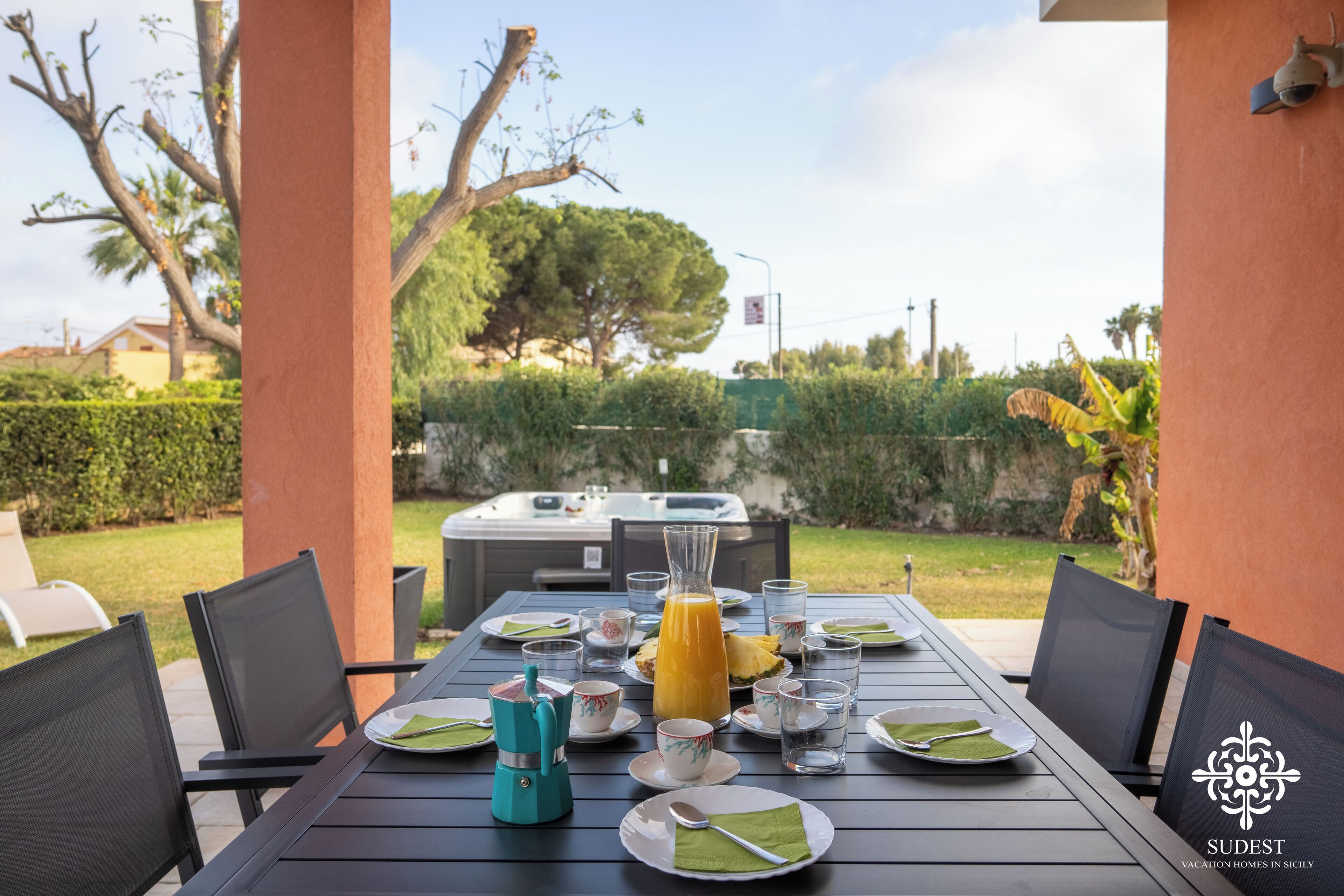 A dining table set for four with plates, glasses, and a coffee maker.