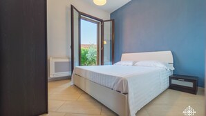 A bedroom with a bed, a nightstand, a window, and a door. - Villa Seaside - Dimora con jacuzzi a 200mt dal mare (Syracuse)
