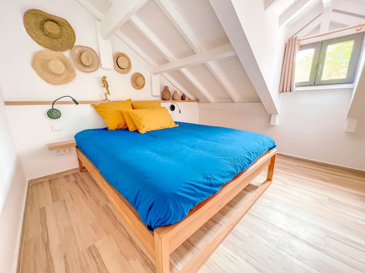 A bedroom with a wooden bed, blue bedding, and a sloped ceiling with skylight.