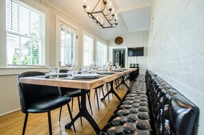 A dining area with a long wooden table set for six, black upholstered chairs, and a black leather bench along the wall.