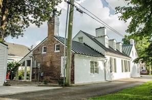 Ein zweistöckiges Haus mit Backsteinfassade und weißem Außenputz, mit einer Veranda und einem Schornstein.