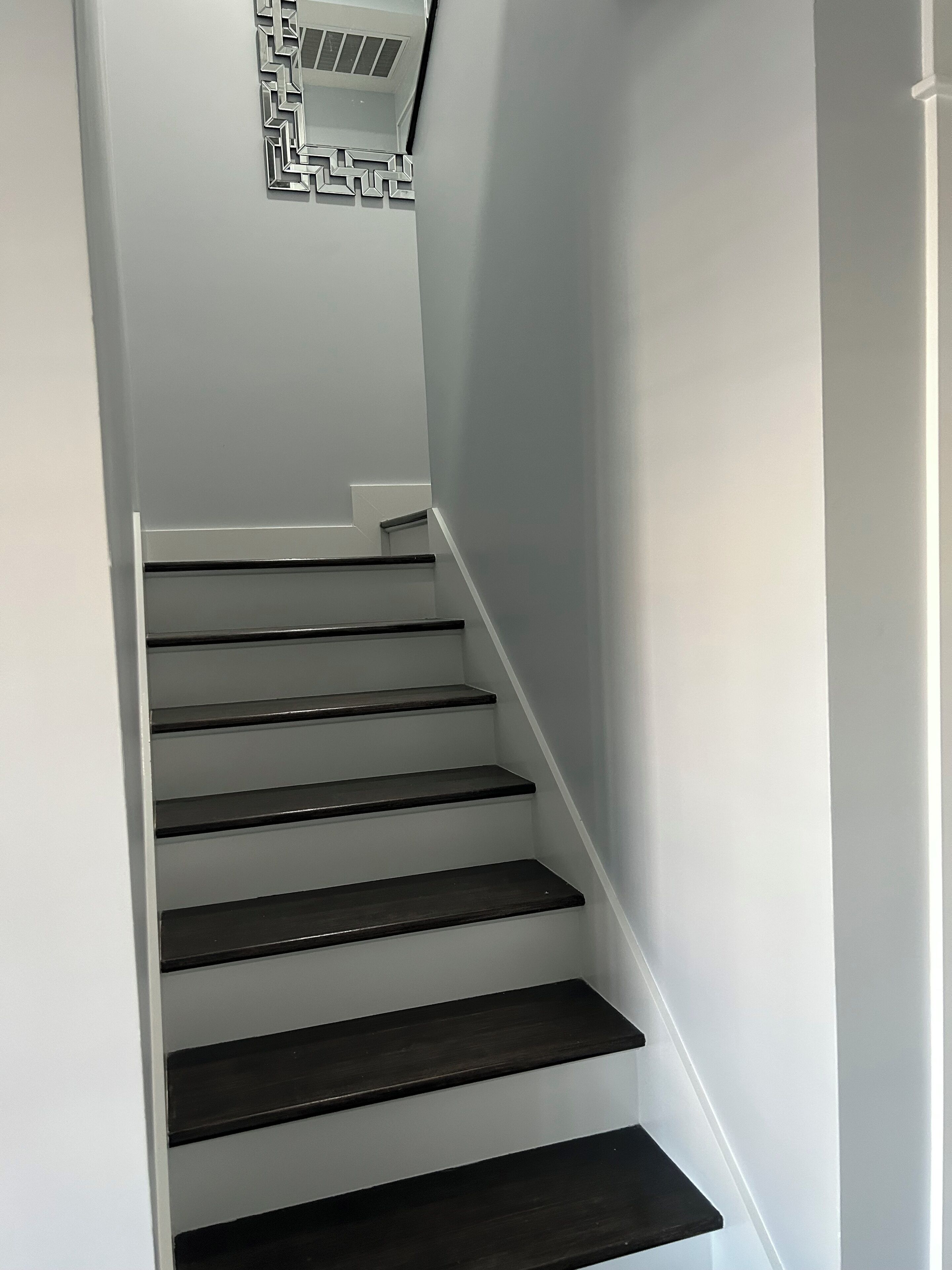 A staircase with dark steps and a white wall.