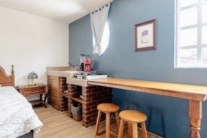 Cozy retreat with a functional layout, featuring a bed, kitchenette, and casual seating area.