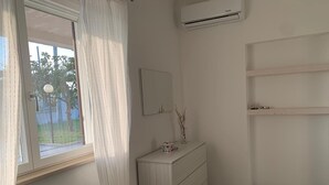 Ein Zimmer mit Fenster, Spiegel, Kommode und Klimaanlage.