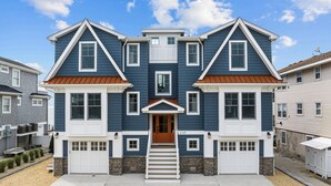 A two-story house with a front porch, a garage, and a driveway. - Beautiful Bayfront w/ Heated Pool & Dock.  6 Bedrooms, all w/ Ensuite Bathrooms. (Ship Bottom)