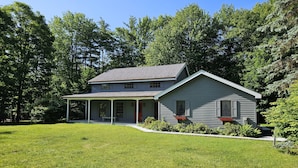 A two-story house with a porch and a well-maintained lawn. - Bolton Landing - 4 Bdrm Vacation Rental (Bolton Landing)