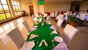 A dining area with tables set for six, each with white chairs, green tablecloths, and a number five placemat. - NASHERA HOTELS DODOMA (Dodoma)