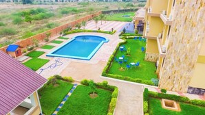 A residential area with a swimming pool, green lawns, and a view of distant buildings. - NASHERA HOTELS DODOMA (Dodoma)