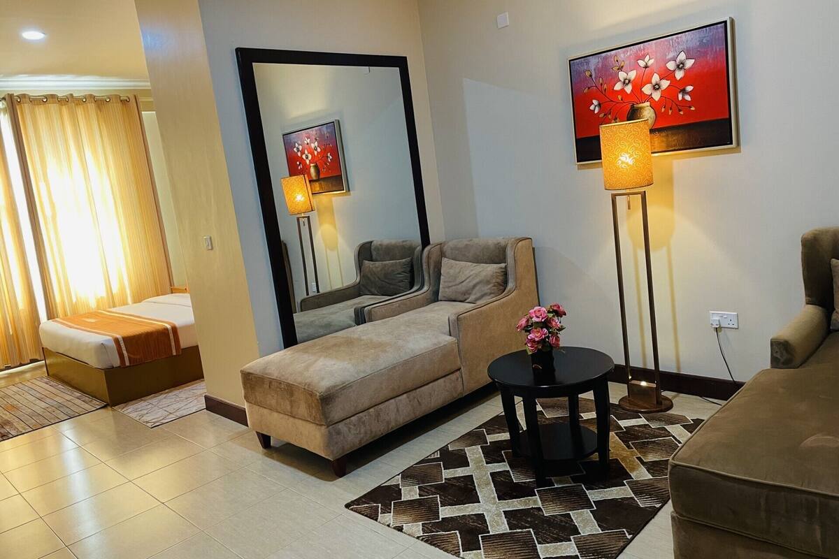 A modern living room with a sofa, a coffee table with a vase, a floor lamp, and a painting on the wall.