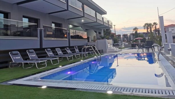 Et moderne hotel med tagpool, liggestole og udsigt over bybilledet.