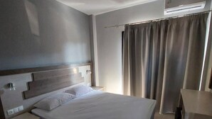 Et moderne hotelværelse med en stor seng, sengeborde, et skrivebord og et klimaanlæg.