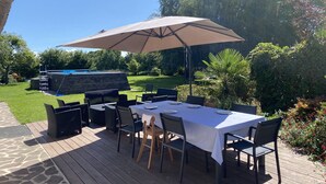 An outdoor patio with a table set for dining, surrounded by chairs and a large umbrella.