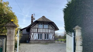 A traditional half-timbered house with a gravel driveway and a gated entrance.