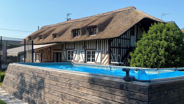A traditional thatched-roof building with a swimming pool.