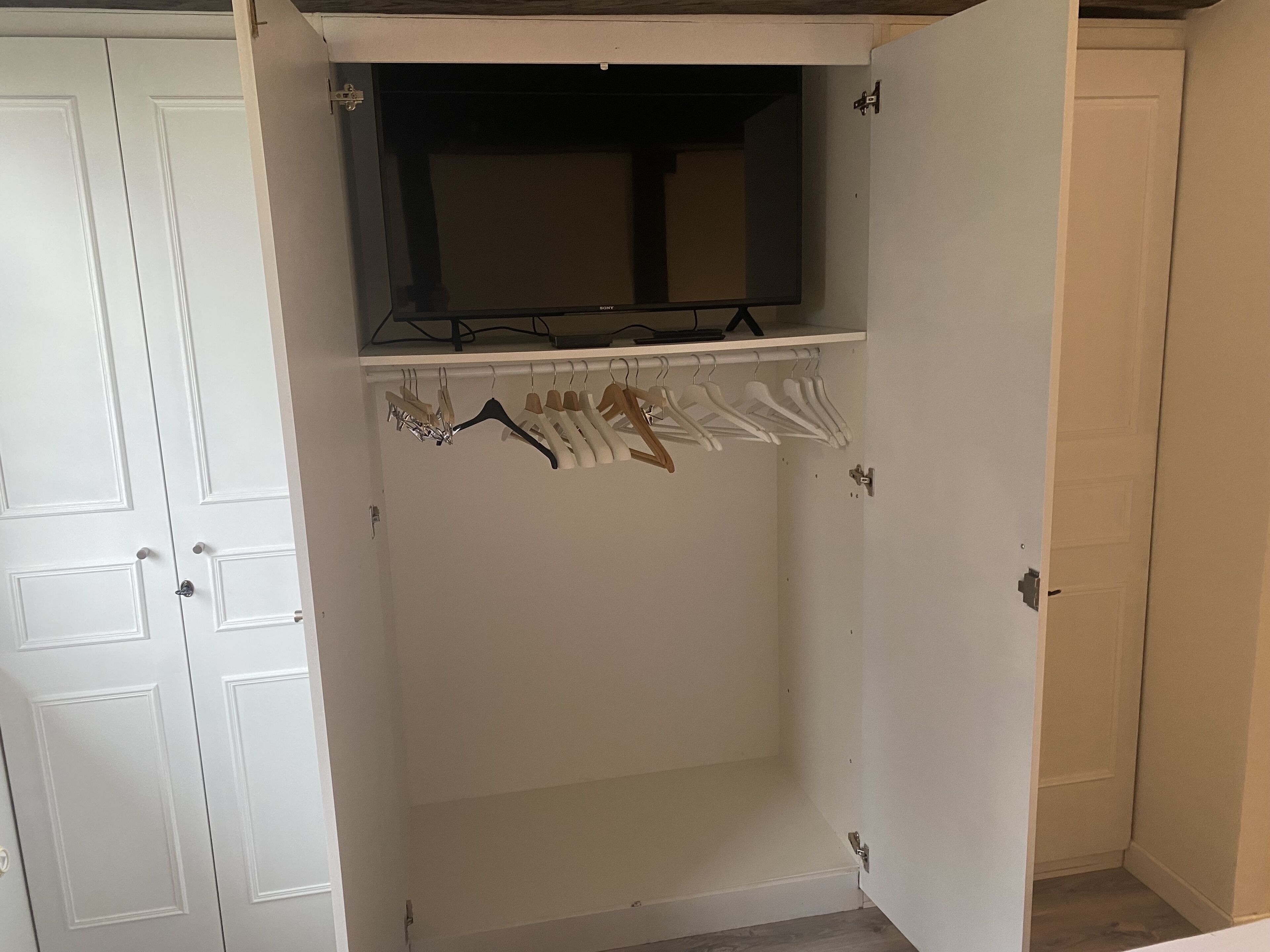 A white closet with a hanging rod and a shelf above it.