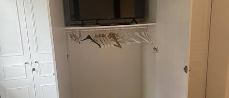A white closet with a hanging rod and a shelf above it.