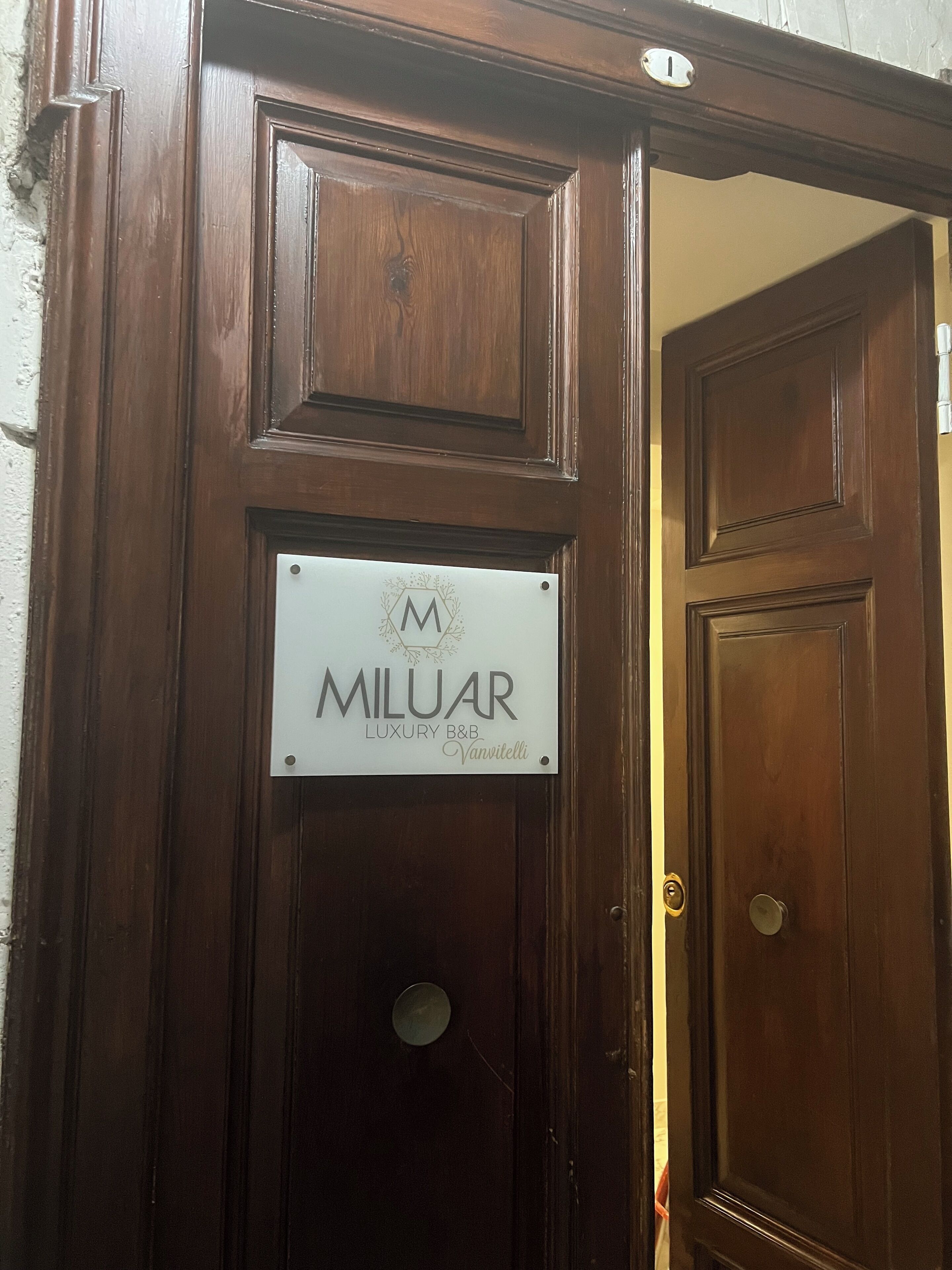 A wooden door with a sign that reads "MILUAR LUXURY B&B Vanvitelli."