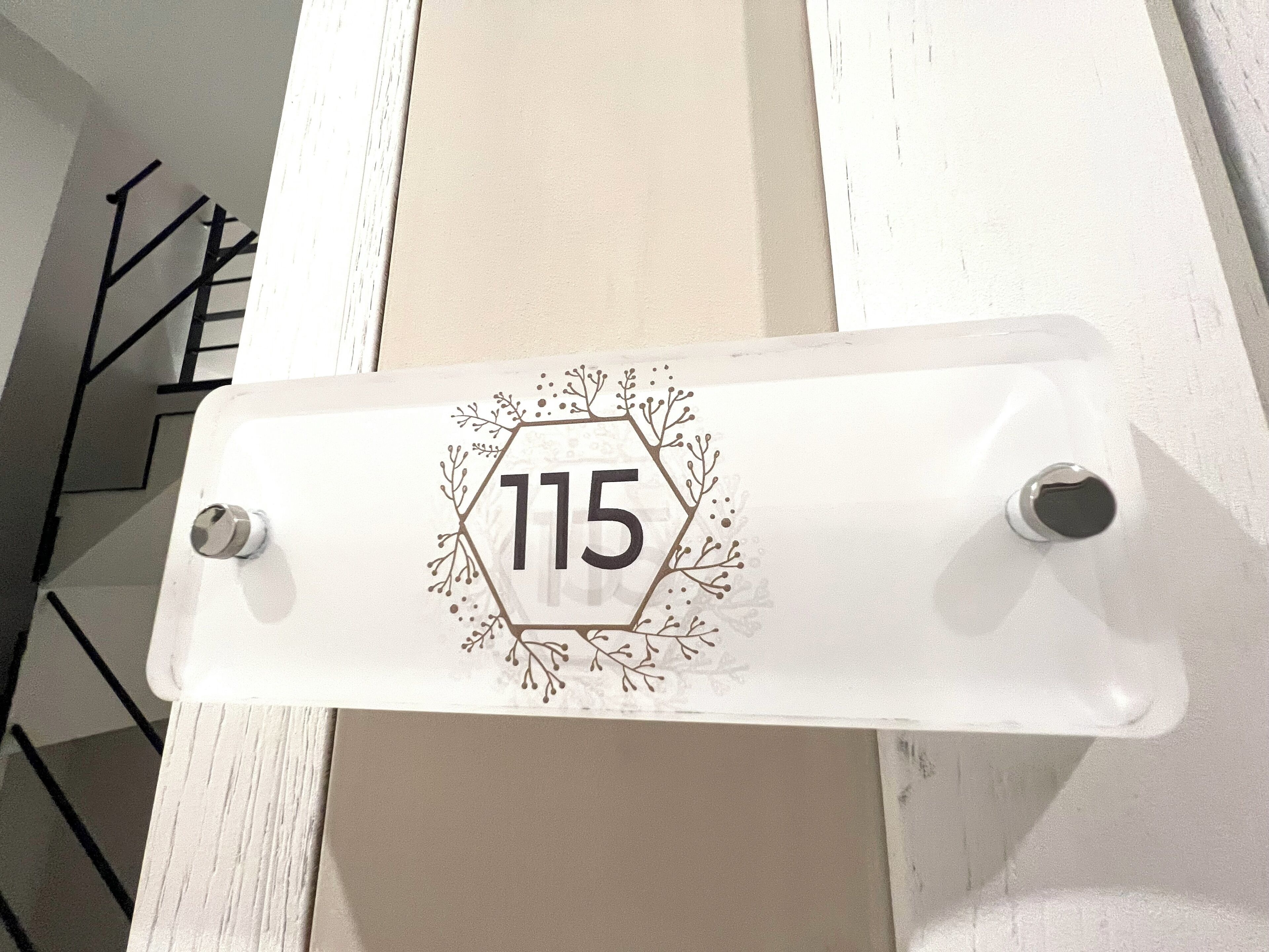 A white door with a number plate displaying '115'.