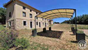 A two-story building with a stone facade and a covered outdoor area with a canopy. - Gîte des Fayettes - Chambost Longessaigne (CHAMBOST LONGESSAIGNE)