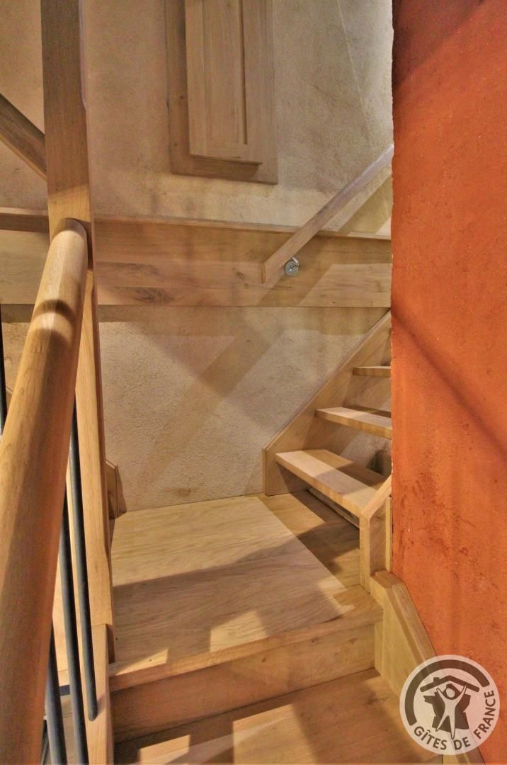 A wooden staircase with a handrail, leading to a landing with a door.