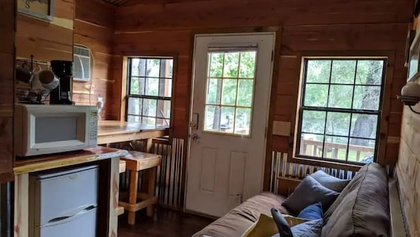 Interior acogedor de una cabaña con kitchenette, comedor y zona de estar con sofá.