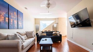 A modern living room with a sofa, coffee table, and a flat-screen TV mounted on the wall. - Modern Apt above Restaurant. Walkable Shops & Bars (Louisville)