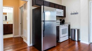 A kitchen with a stainless steel refrigerator, a microwave, an oven, and a trash can. - Modern Apt above Restaurant. Walkable Shops & Bars (Louisville)