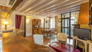 A cozy living room with a wooden table, a television, and a dining area with chairs and a cabinet.