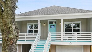 A two-story house with a front porch, a garage, and a staircase leading to the upper floor. - Scenic Sandpiper by the Shore (Long Beach)