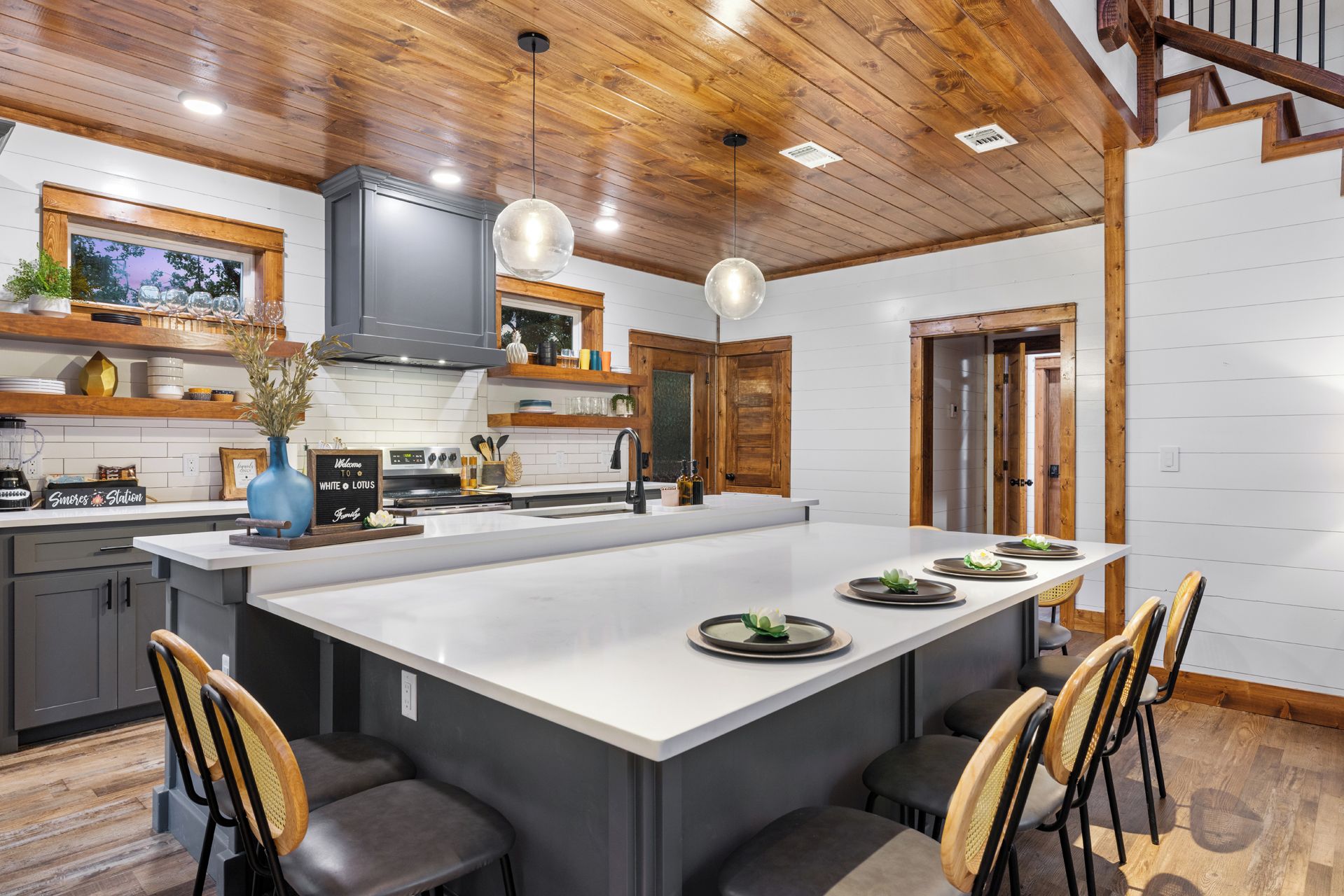 A modern kitchen with a central island, wooden ceiling, and built-in appliances.