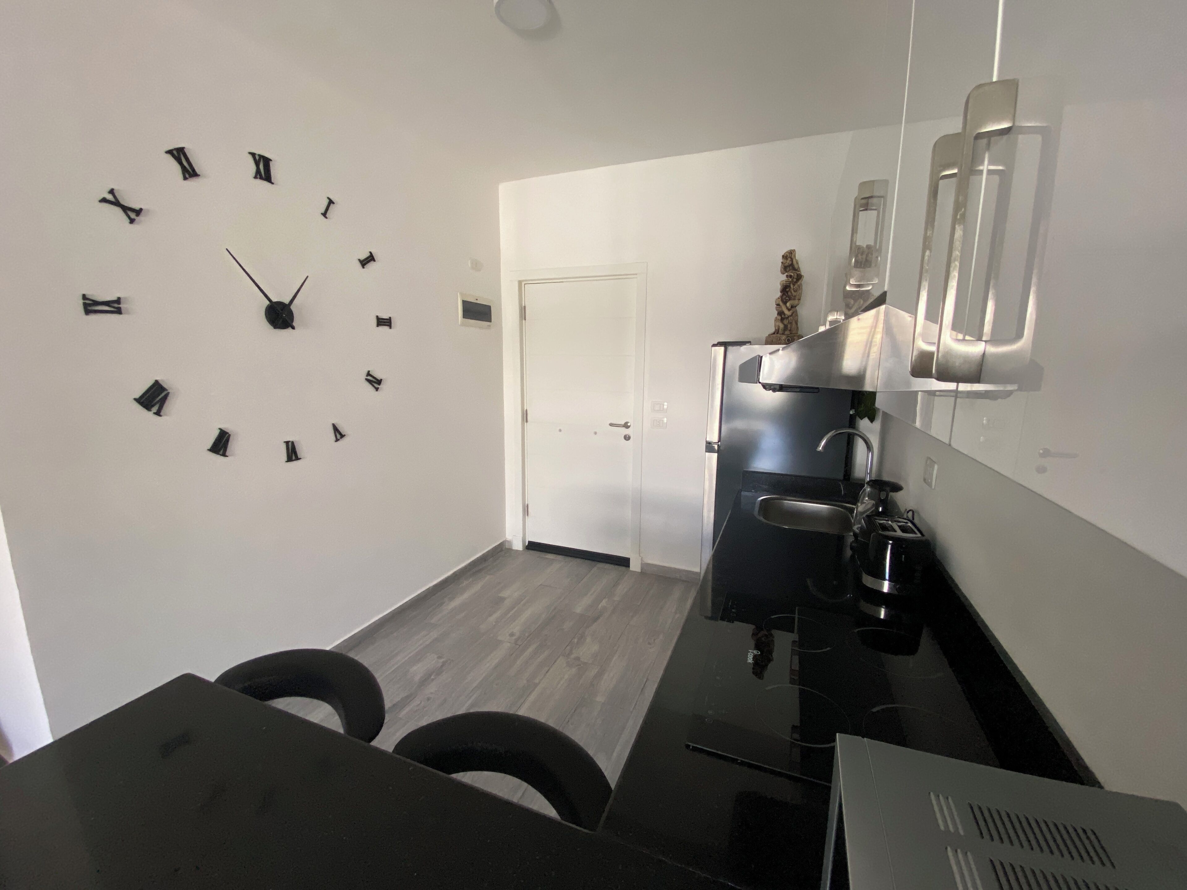 A modern kitchen with a black countertop, stainless steel appliances, and a wall clock.