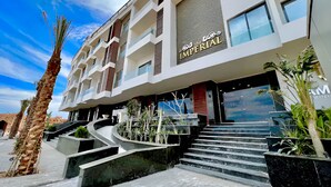 A modern hotel with a prominent entrance, a staircase leading to the entrance, and a clear sky in the background. - 3BR 2BA Escape 4 Pools • Wi-Fi • Onsite Shop • Onsite Restaurant • Near El Gouna (Red Sea Governorate)