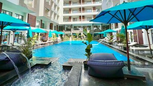A hotel pool area with multiple levels of balconies, lounge chairs, and umbrellas. - 3BR 2BA Escape 4 Pools • Wi-Fi • Onsite Shop • Onsite Restaurant • Near El Gouna (Red Sea Governorate)