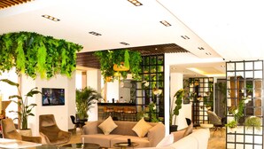 A modern lobby with a sofa, chairs, a coffee table, and a TV screen. - 3BR 2BA Escape 4 Pools • Wi-Fi • Onsite Shop • Onsite Restaurant • Near El Gouna (Red Sea Governorate)