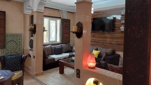 Una sala de estar acogedora con un sofá, una mesa de centro y un televisor montado en la pared.