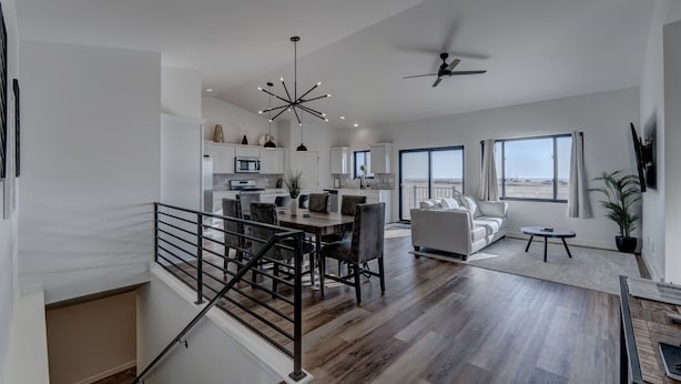 A spacious living area with a dining table, sofa, and a staircase with a railing. - Luxury Rapid City Home #2 (Rapid City)