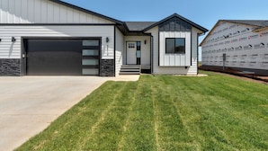 A modern two-story building with a garage, a covered porch, and a well-maintained lawn. - Luxury Rapid City Home #2 (Rapid City)