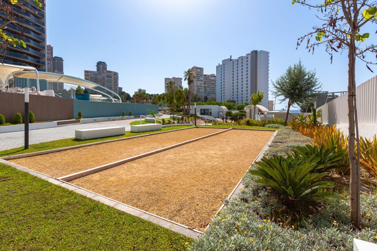Un patio con un jardín central, rodeado de edificios modernos y un cielo despejado.