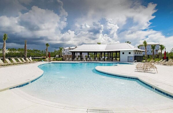 A swimming pool with lounge chairs and a covered pavilion.
