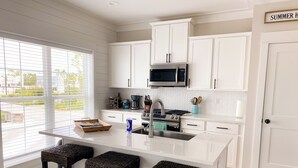 Una cocina moderna con armarios blancos, una isla central con taburetes, un microondas y una cafetera.