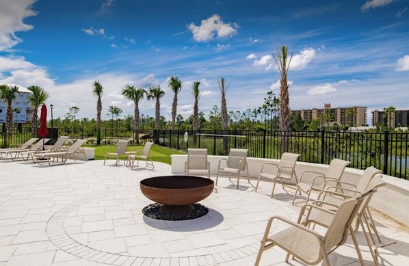 Un patio al aire libre con sillones, una chimenea y vistas a palmeras y edificios.