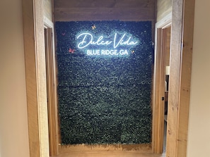 A doorway with a neon sign reading 'Dulce Vida BLUE RIDGE GA' against a backdrop of green foliage.