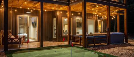 A two-story wooden building with a covered patio area featuring a miniature golf setup.