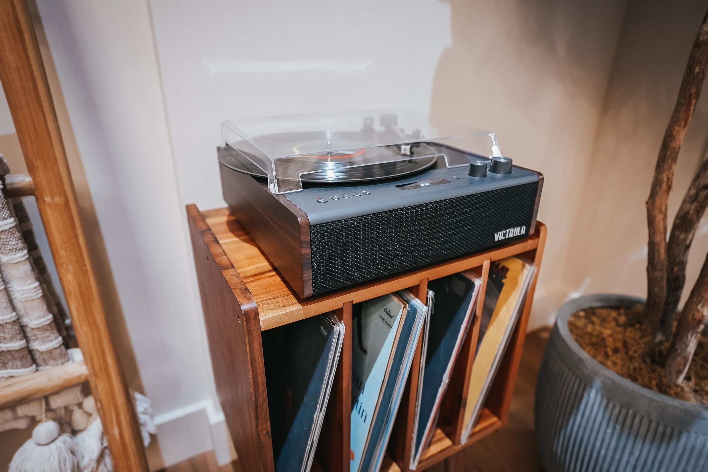 Um toca-discos sobre uma prateleira de madeira com discos de vinil abaixo.