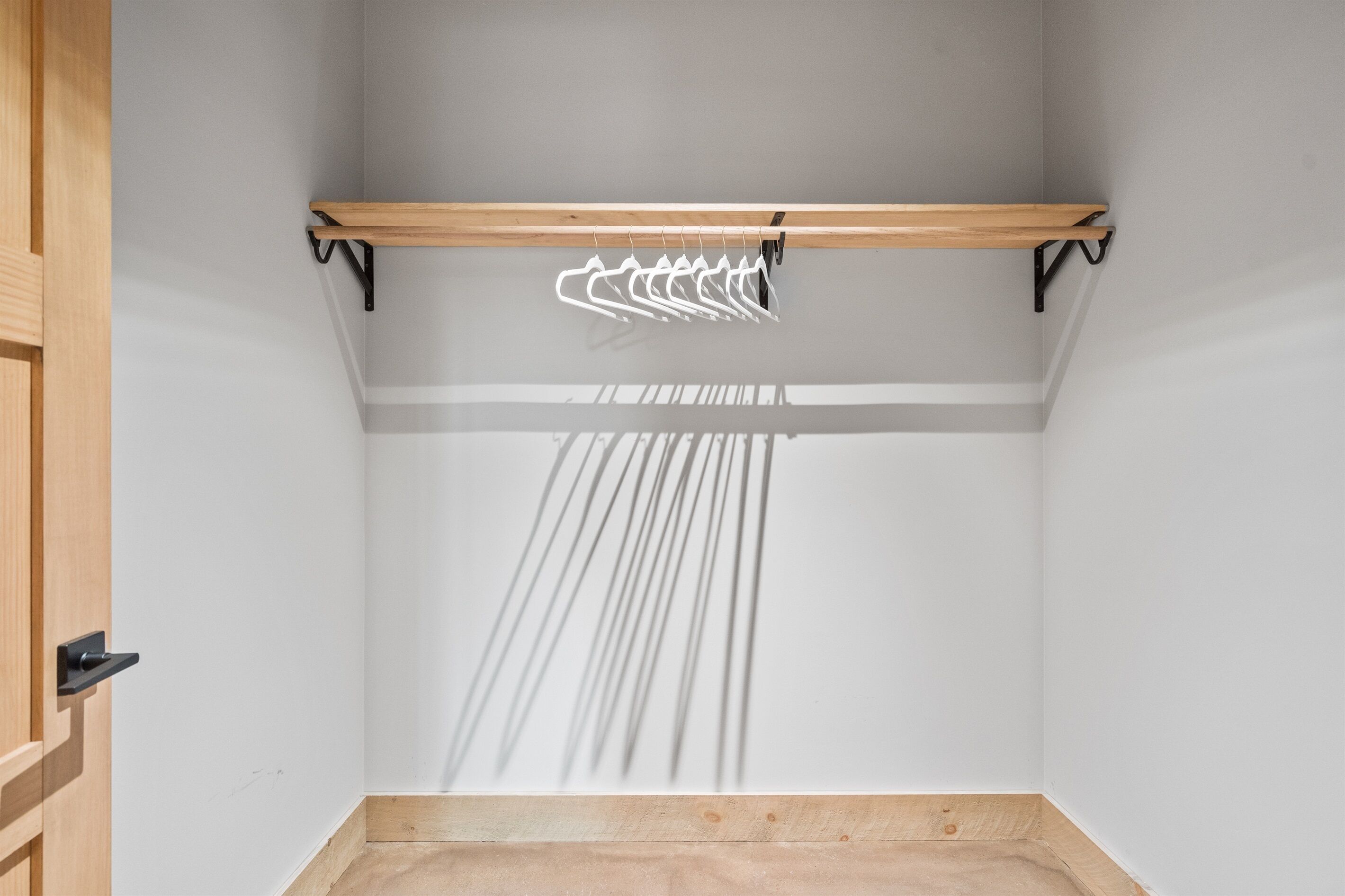 A room with a wooden ceiling, a black metal rack, and a wooden floor.