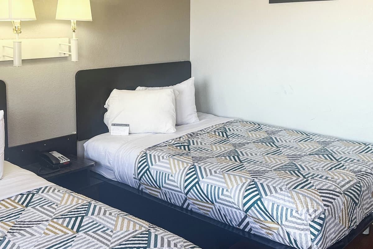 Ein Hotelzimmer mit Bett, Nachttisch, Lampe und Wandleuchte.