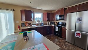 A kitchen with wooden cabinets, a stainless steel refrigerator, a microwave, and a stove.